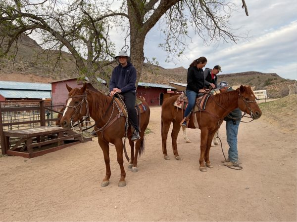 Riders following a wrangler along a desert trail past Joshua trees at the ranch