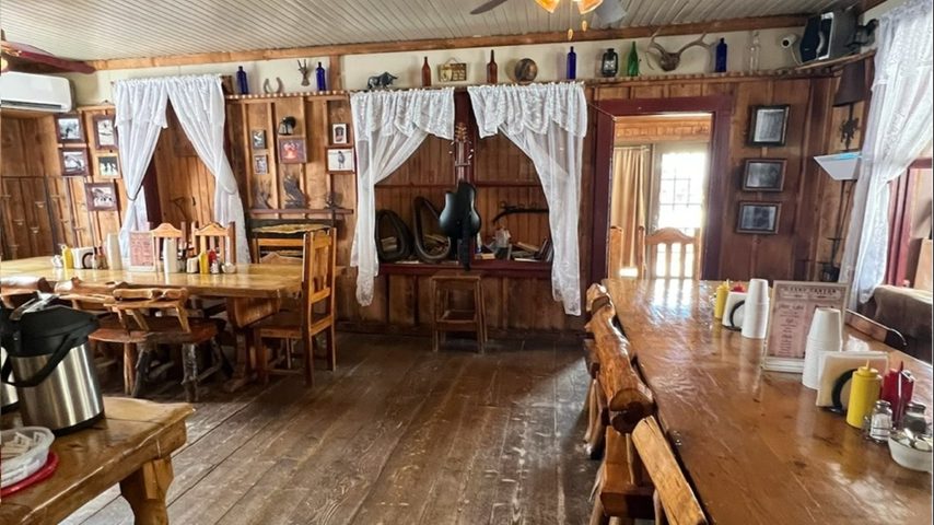 The ranch house dining room with long wooden tables set for dinner